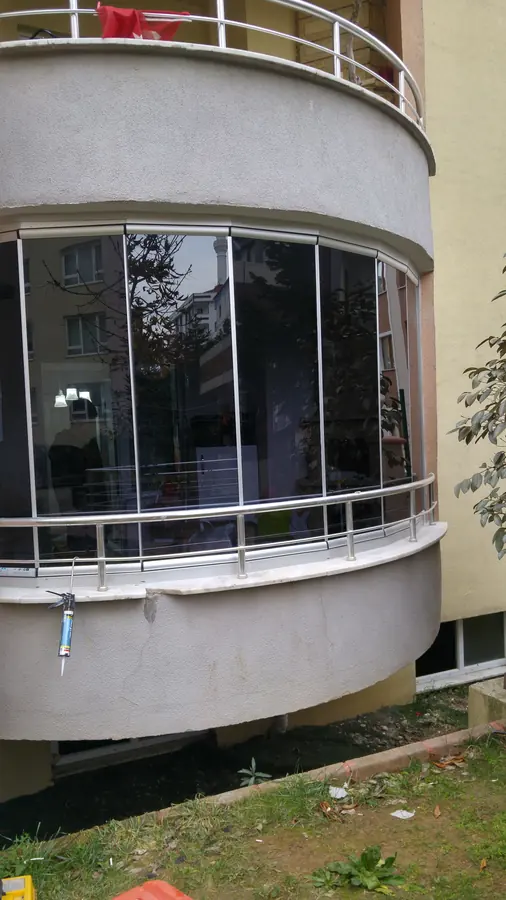 Kavisli balkonda füme katlanır cam balkon